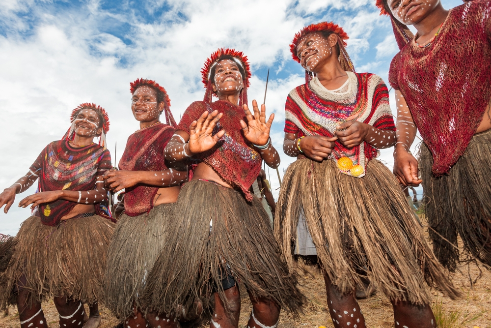 Group of young girls from the Dani tribe dancing and singing