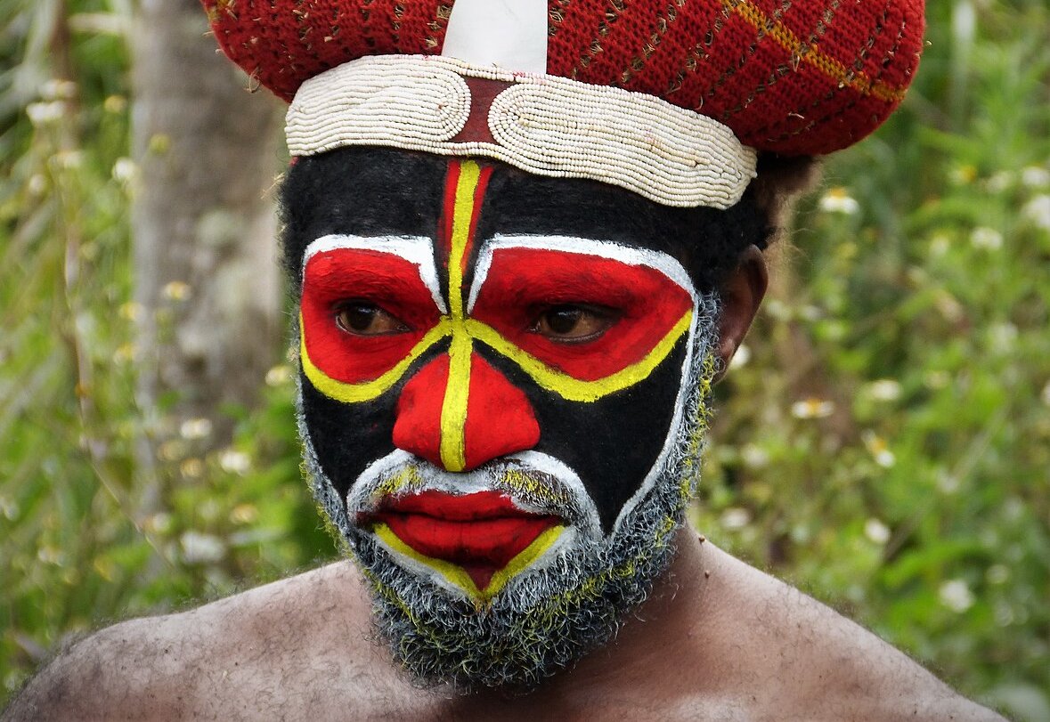This image captures a person from Melanesia wearing vibrant traditional face paint