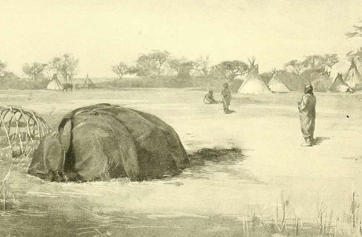 A sweat lodge in a field with natives nearby