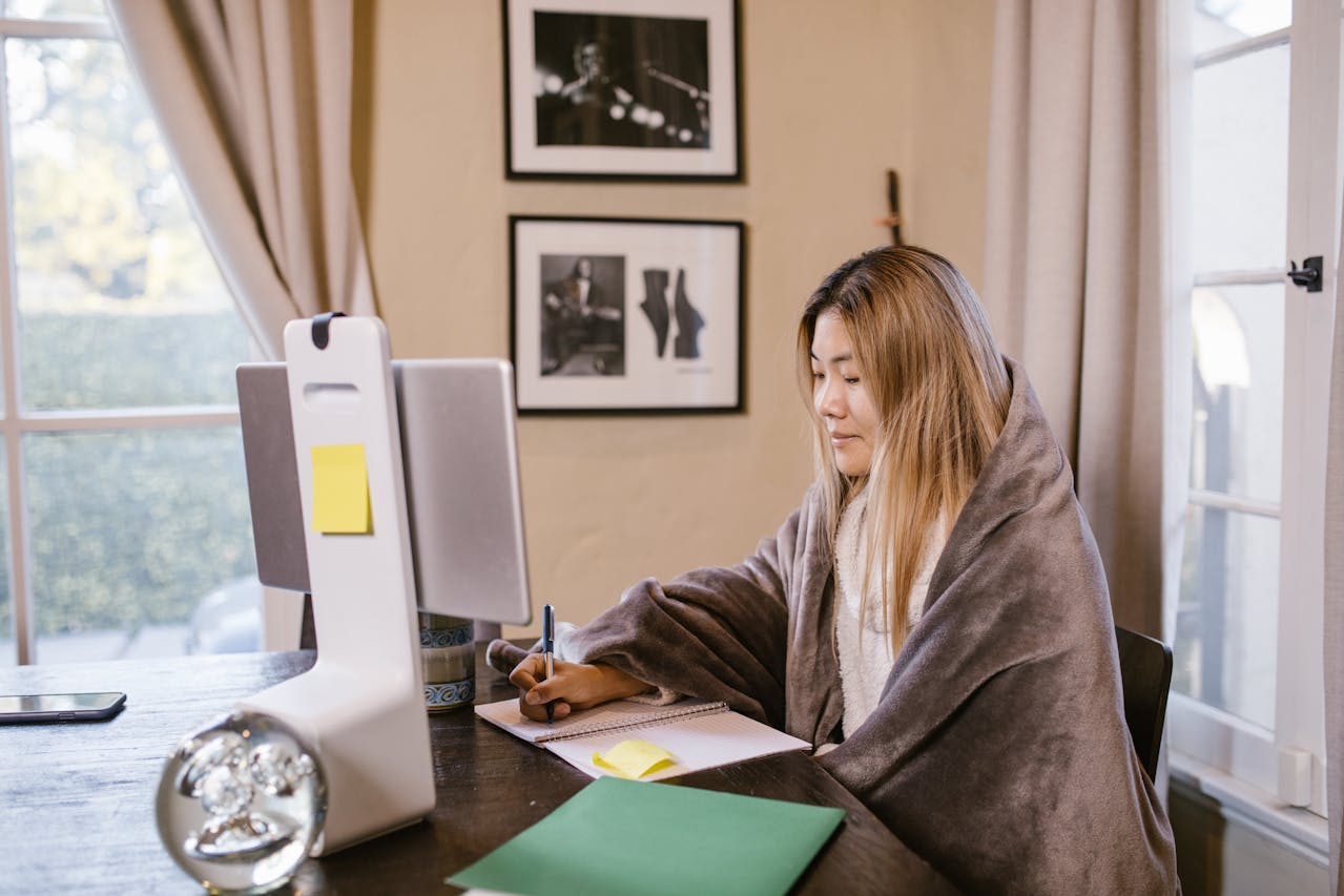 Photograph of a Woman Writing on a Notebook