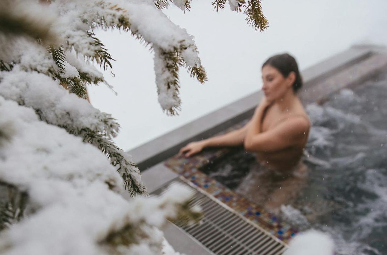 A Woman Soaking on a Jacuzzi Near Snow Covered Tree