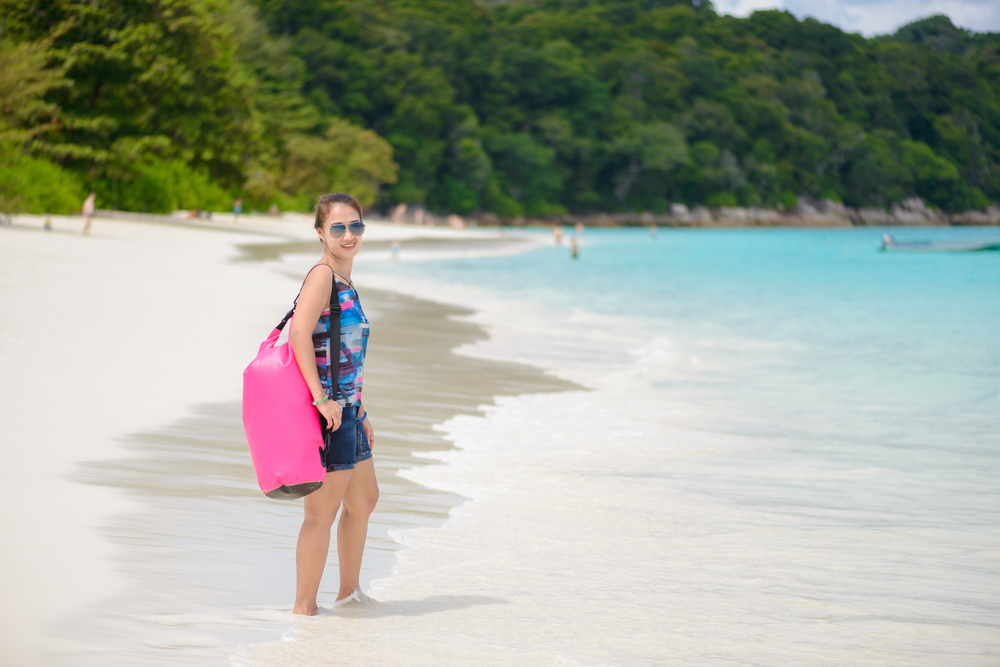 Woman standing with Dry Bag on the beach.