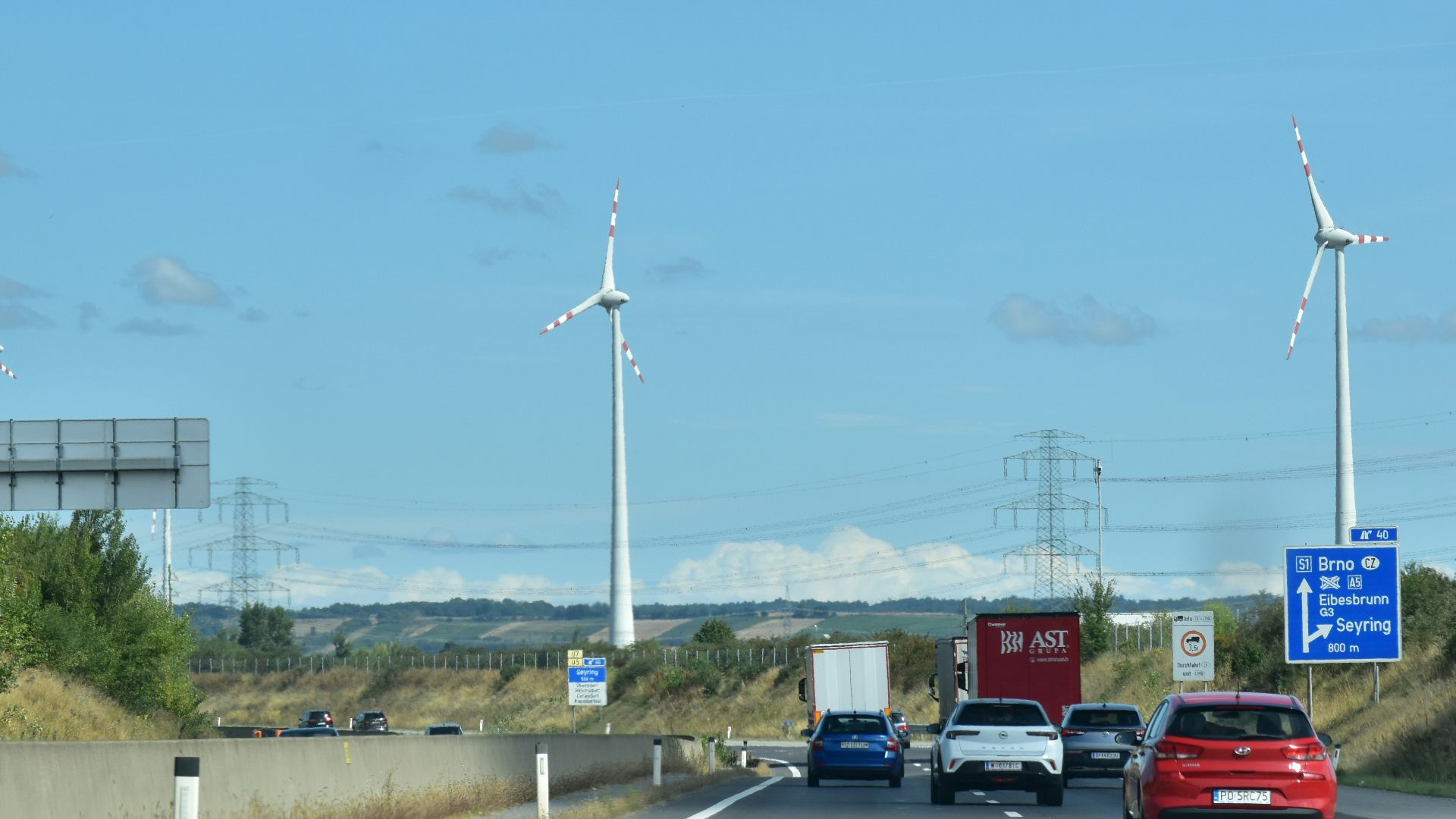 Cars driving on highway with wind turbines in background