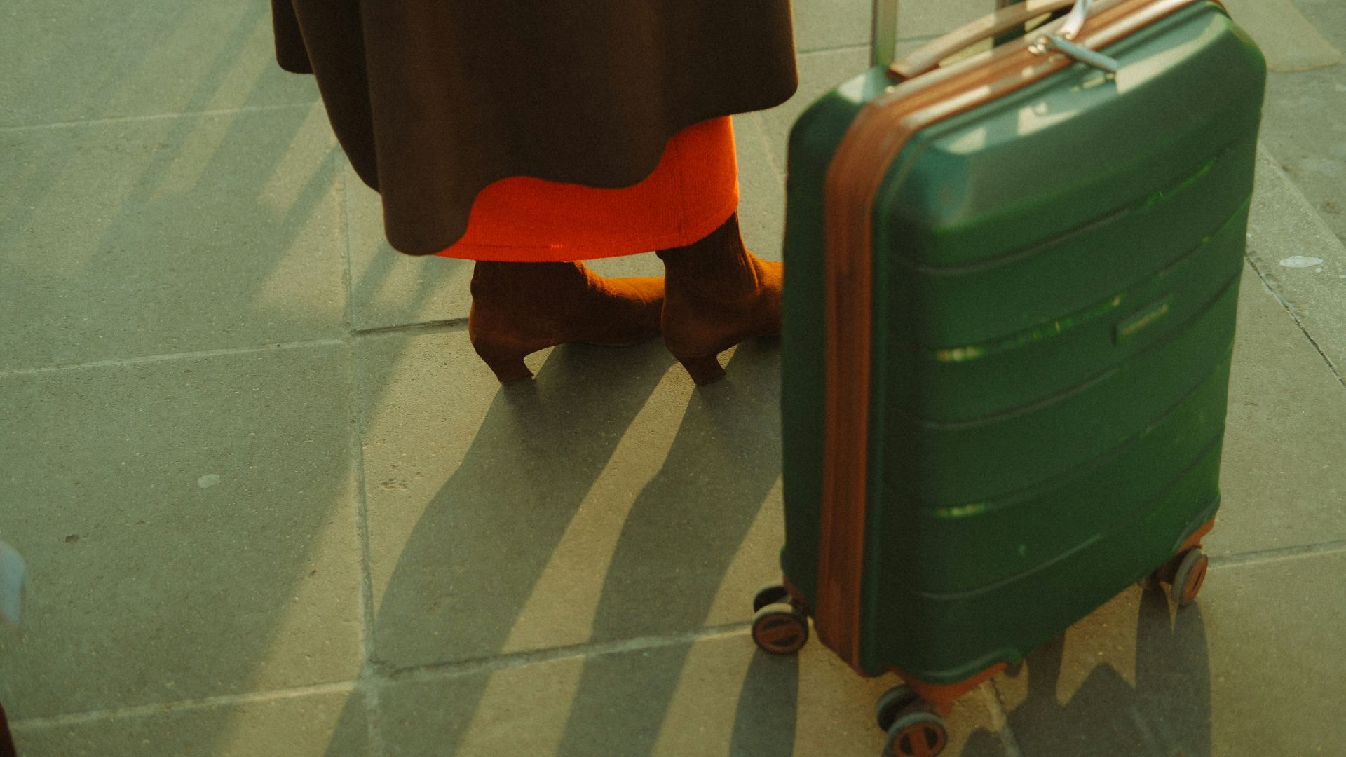 A woman standing next to a green suitcase