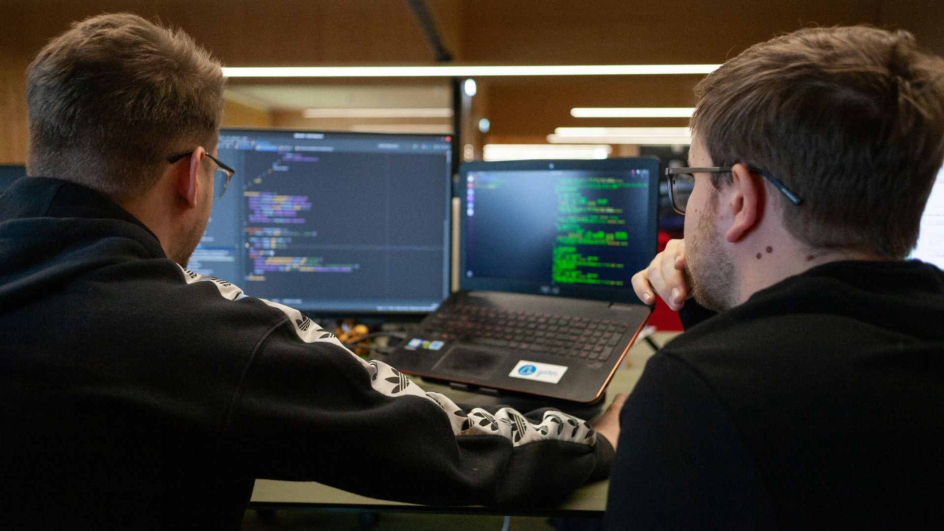 two men sitting in front of a laptop computer