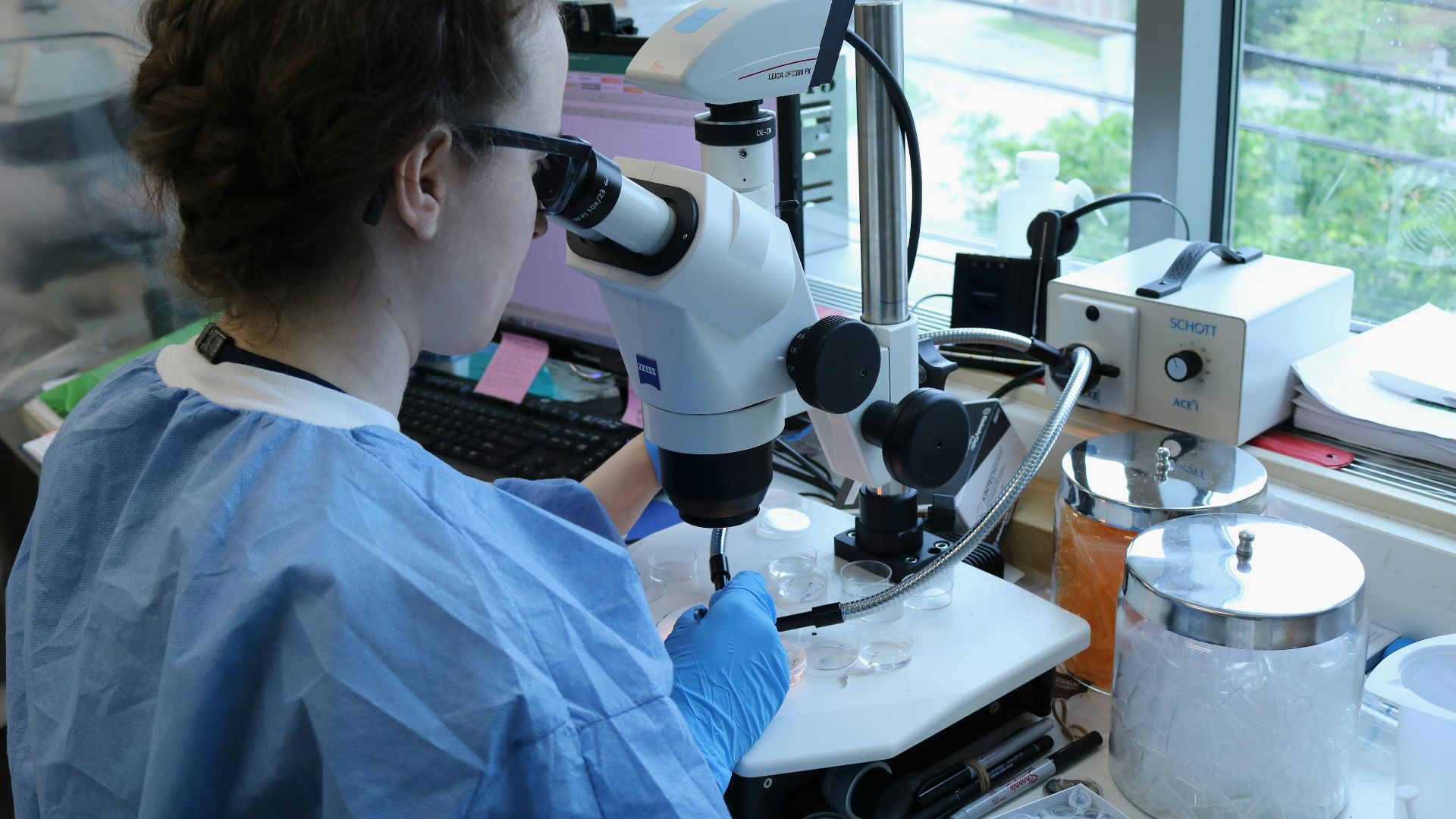 a woman in a lab coat looking through a microscope