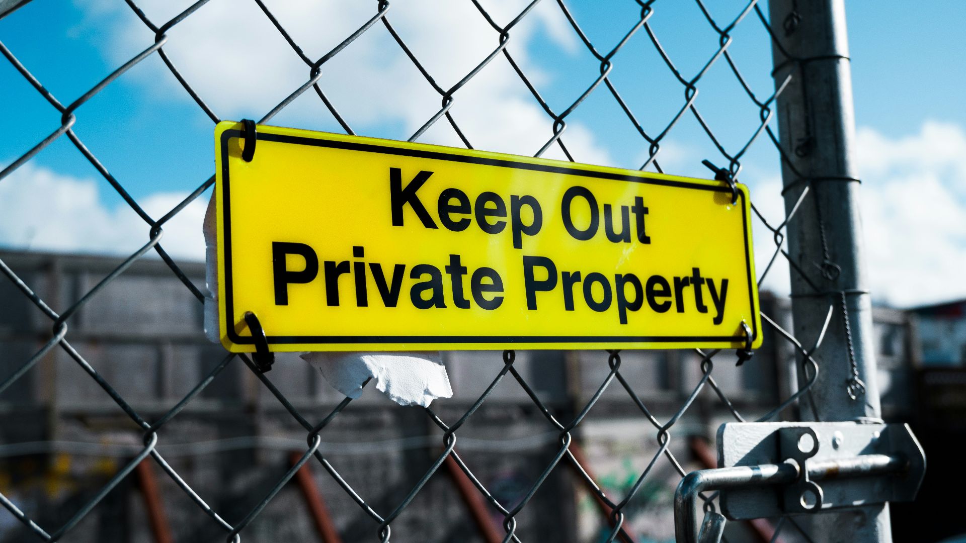 a yellow keep out private property sign on a chain link fence