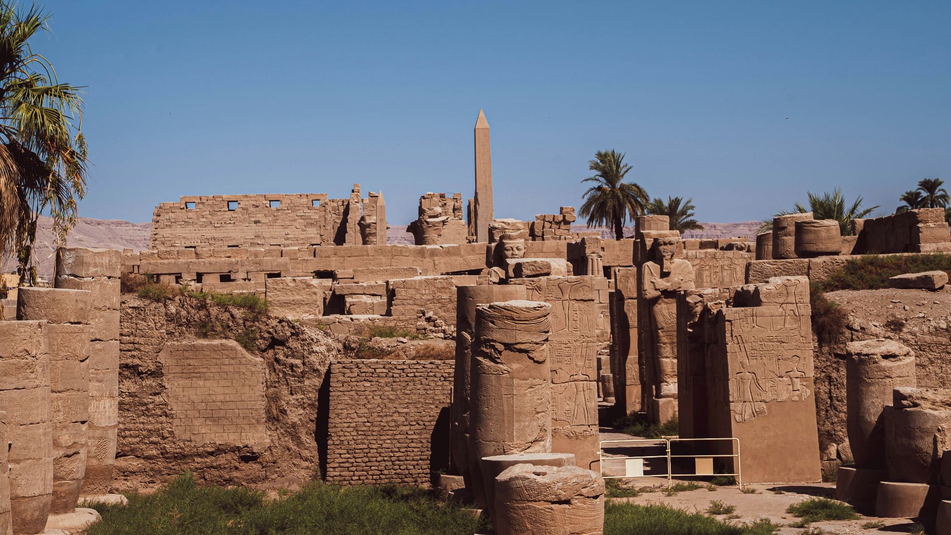 a stone building with pillars with Karnak in the background
