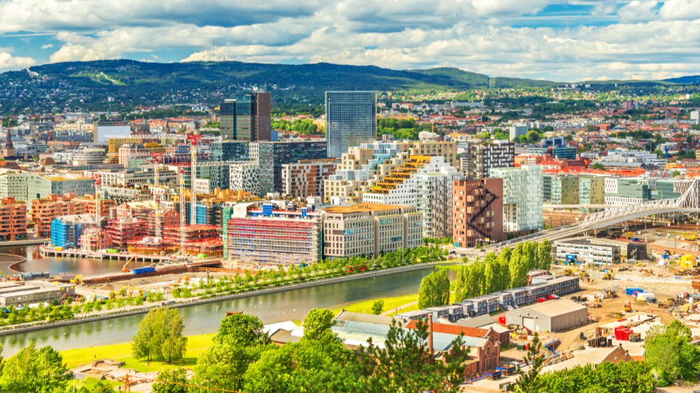 The image showcases a Vibrant urban scene of Oslo, Norway captured from a high vantage point. The city appears well-developed with a mix of modern and historic architecture.
