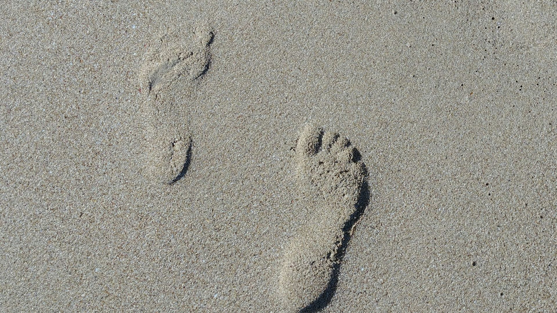 a pair of footprints in the sand on a beach