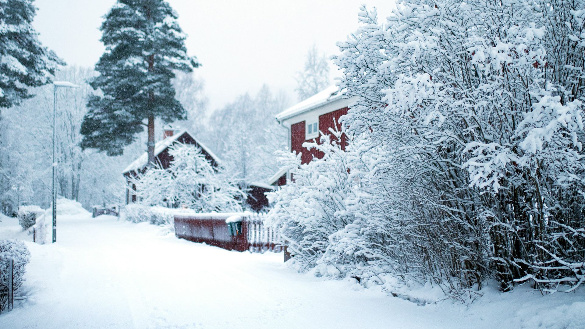 a snow covered road with a house in the distance