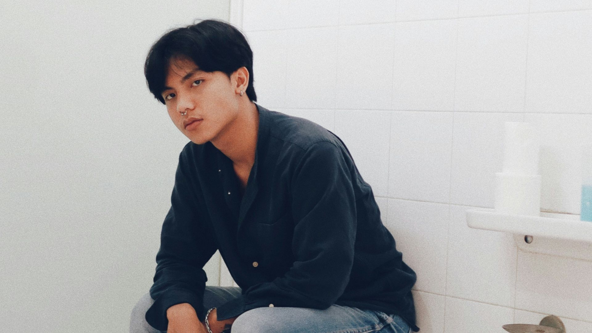 man in blue dress shirt and blue denim jeans sitting on white ceramic toilet bowl