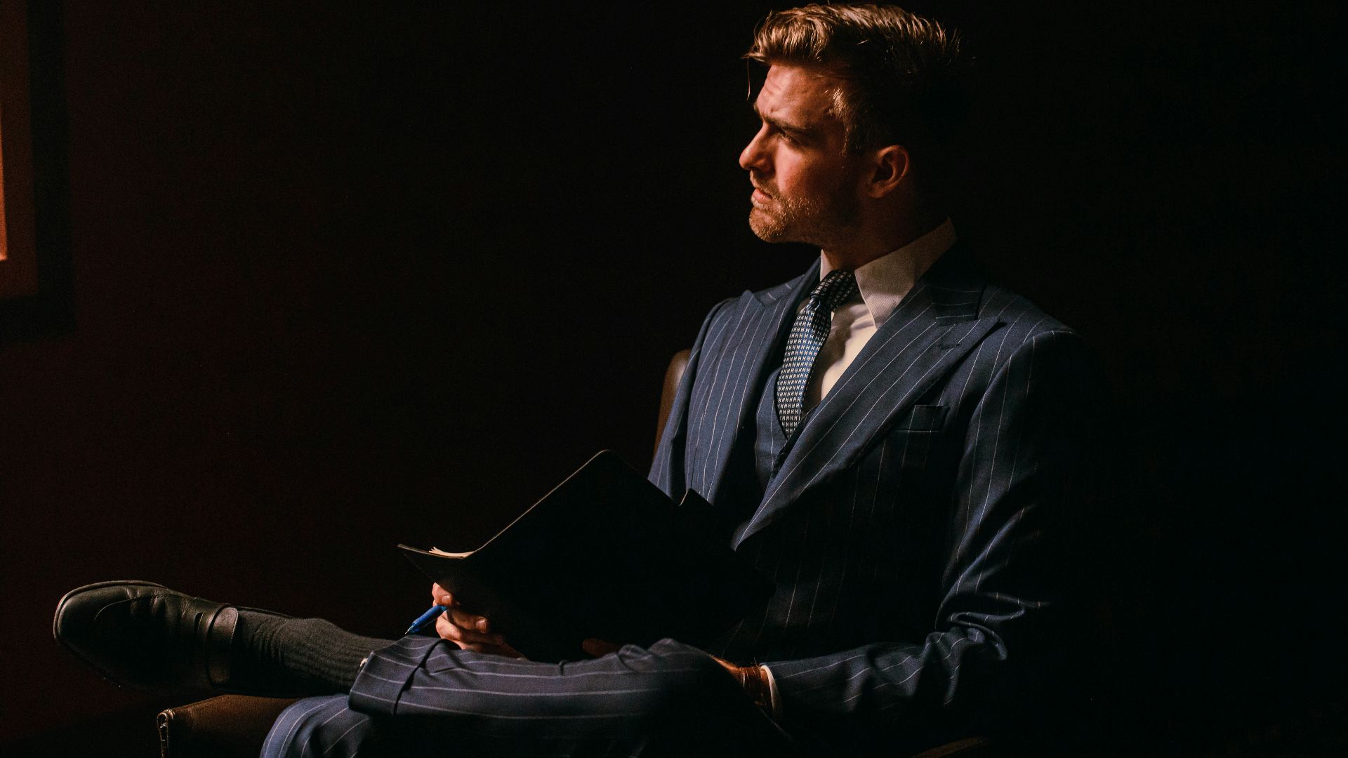 a man in a suit sitting in a dark room