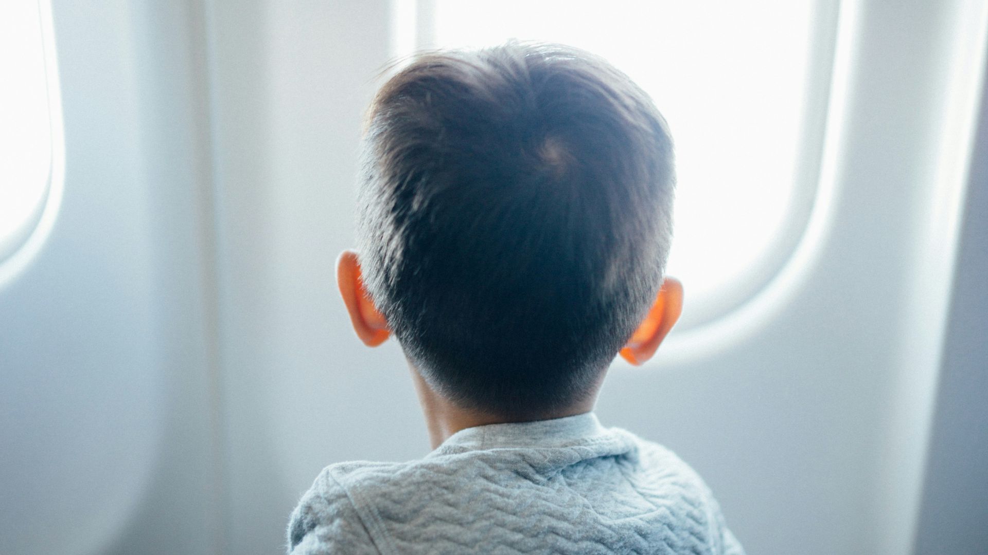 boy sitting on plane seat while viewing window
