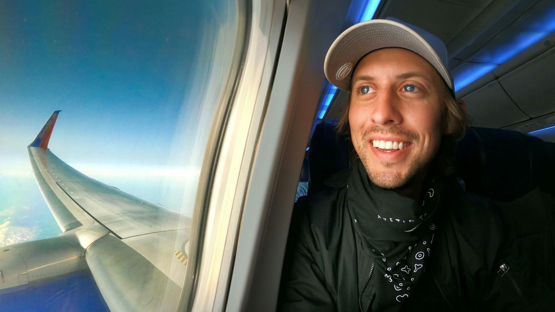 smiling woman in black jacket wearing blue cap