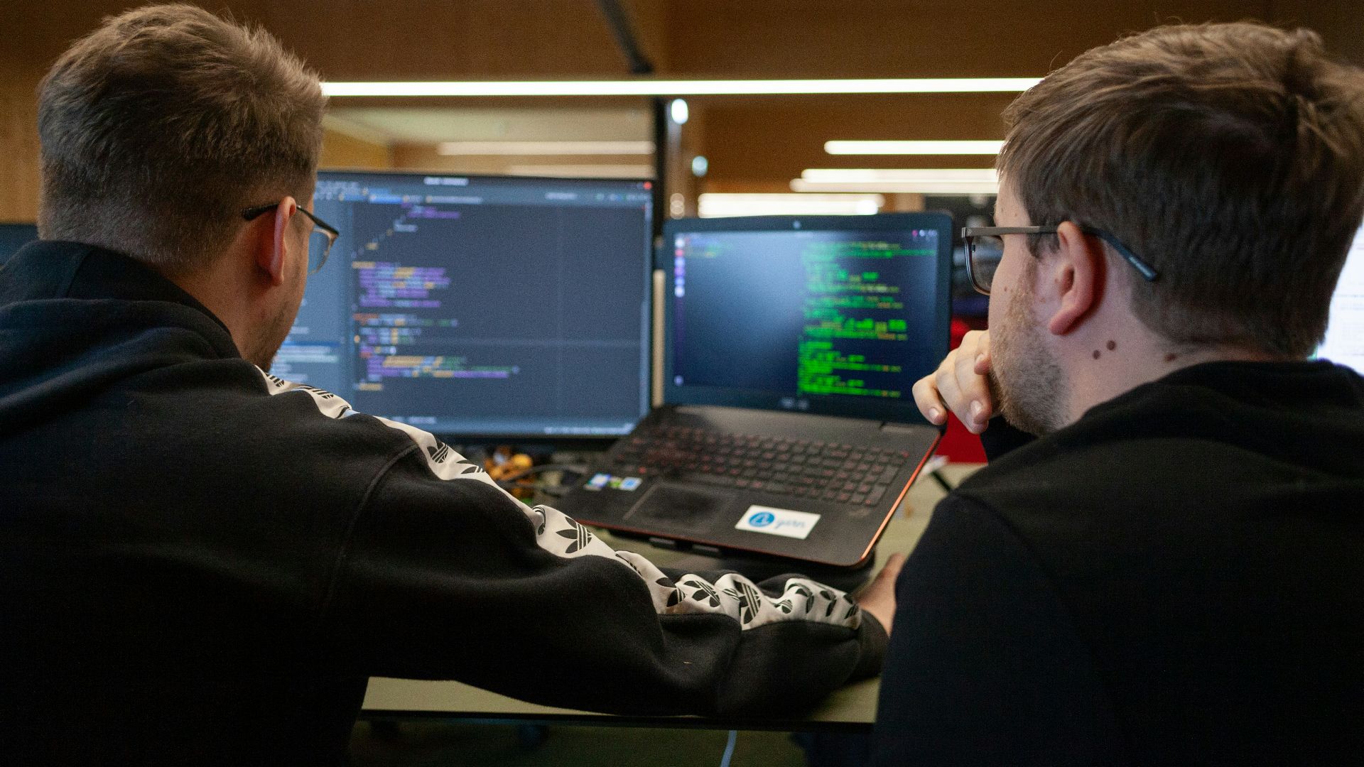 two men sitting in front of a laptop computer