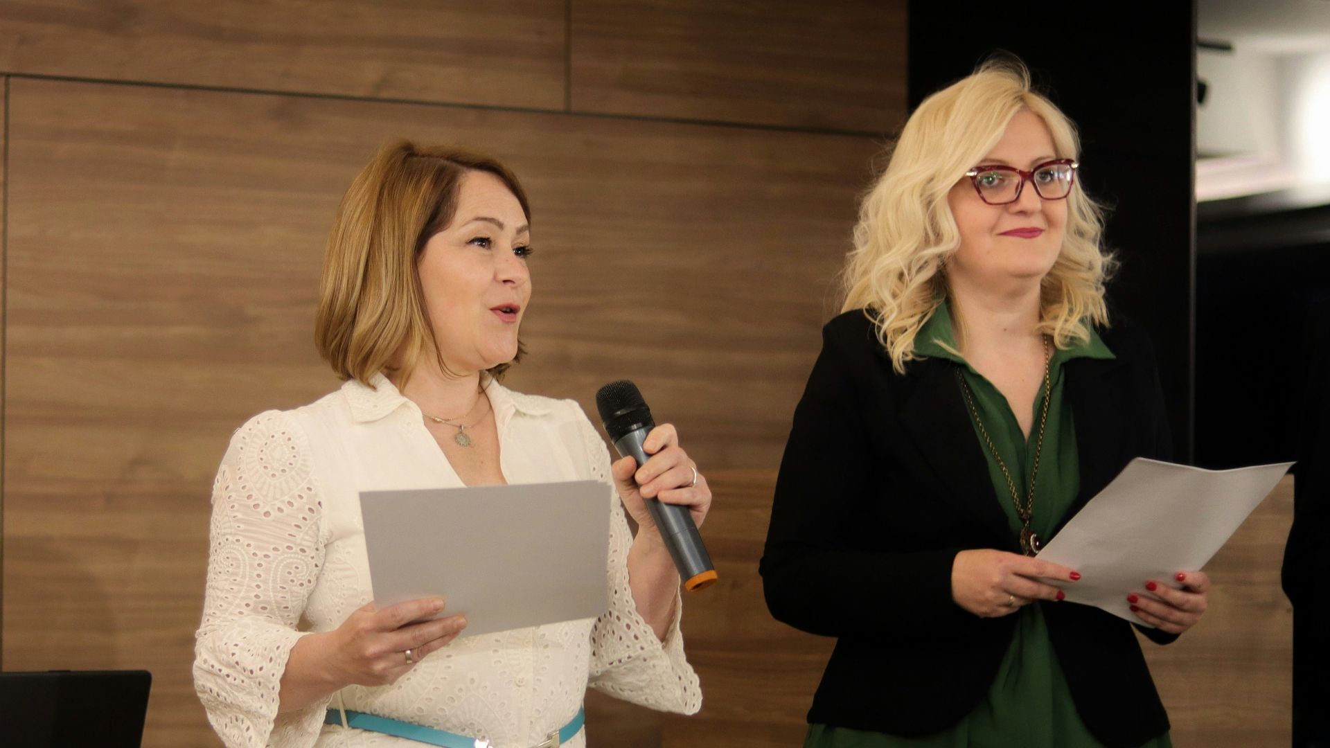 a woman standing next to a woman holding a microphone