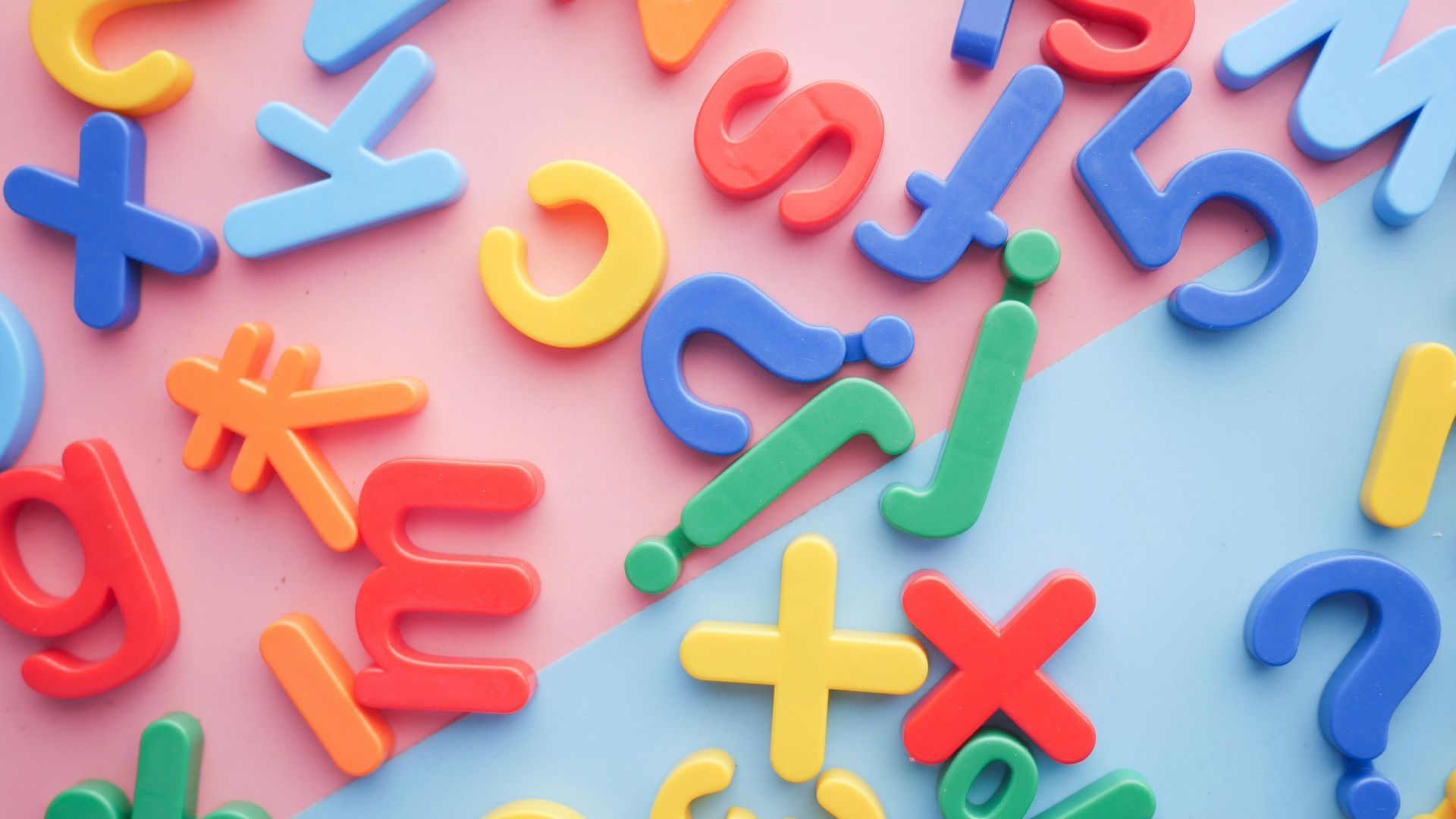 a pile of plastic letters and numbers on a pink and blue background