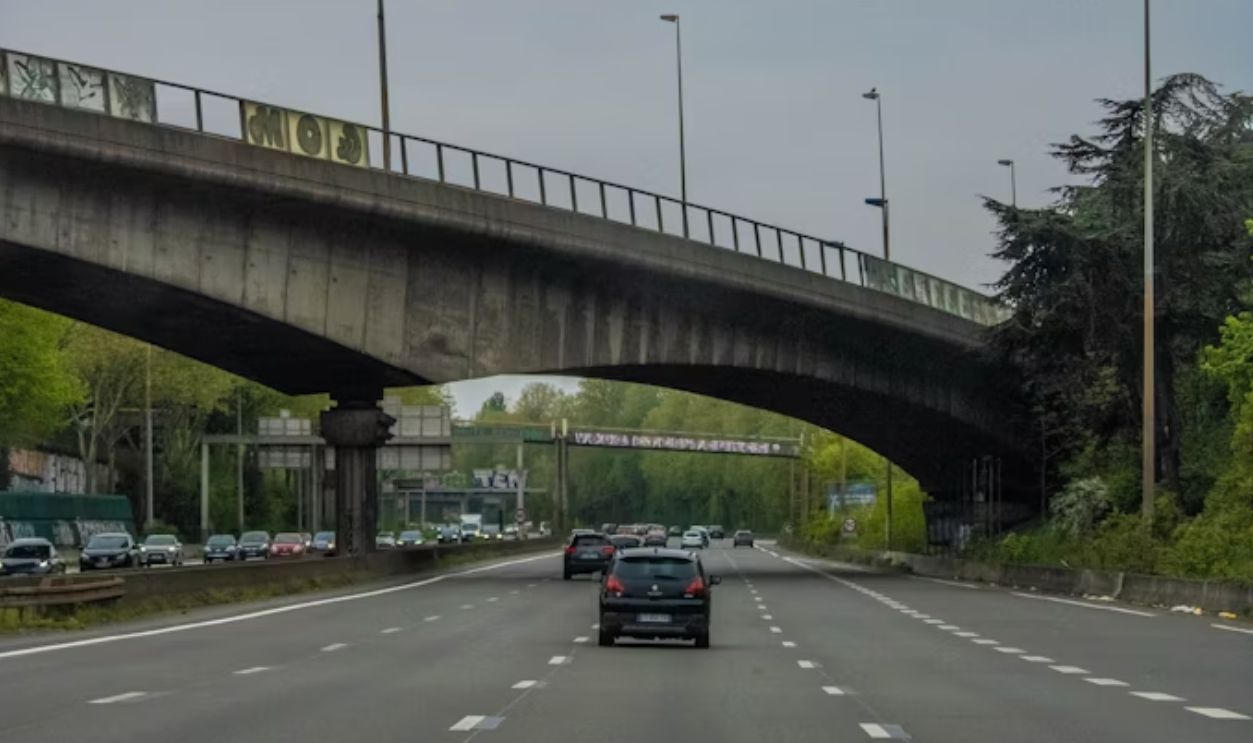 A bridge over a highway with cars driving under it