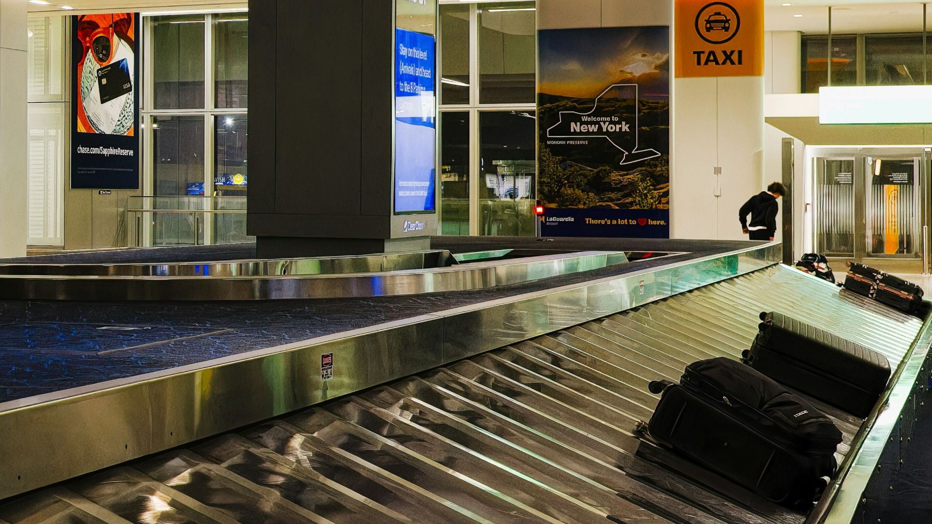 a luggage carousel in an airport with a large screen