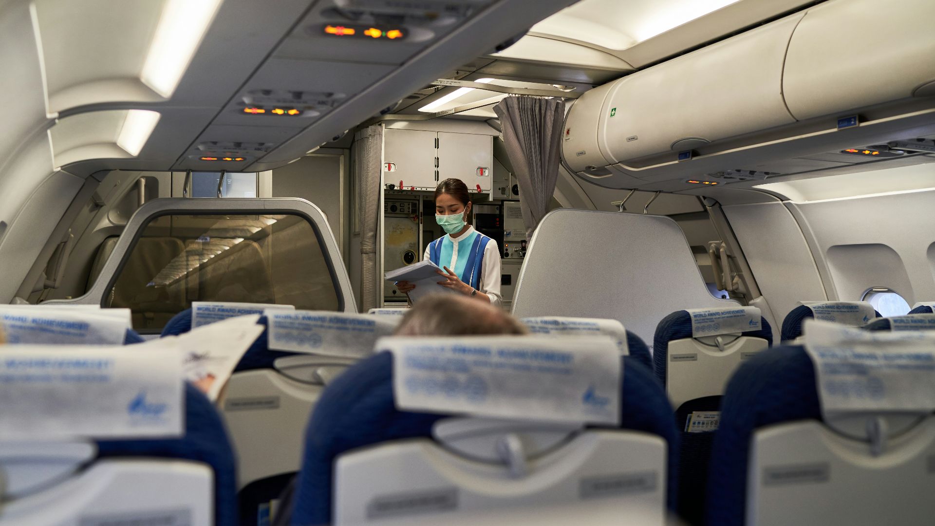 a woman in a face mask sitting on an airplane