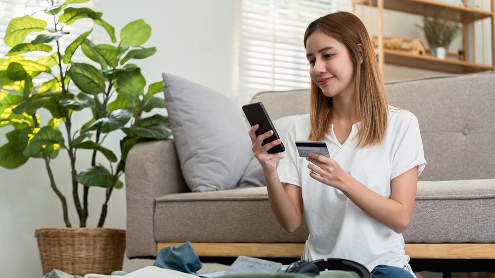 Happy young woman with credit card booking vacation