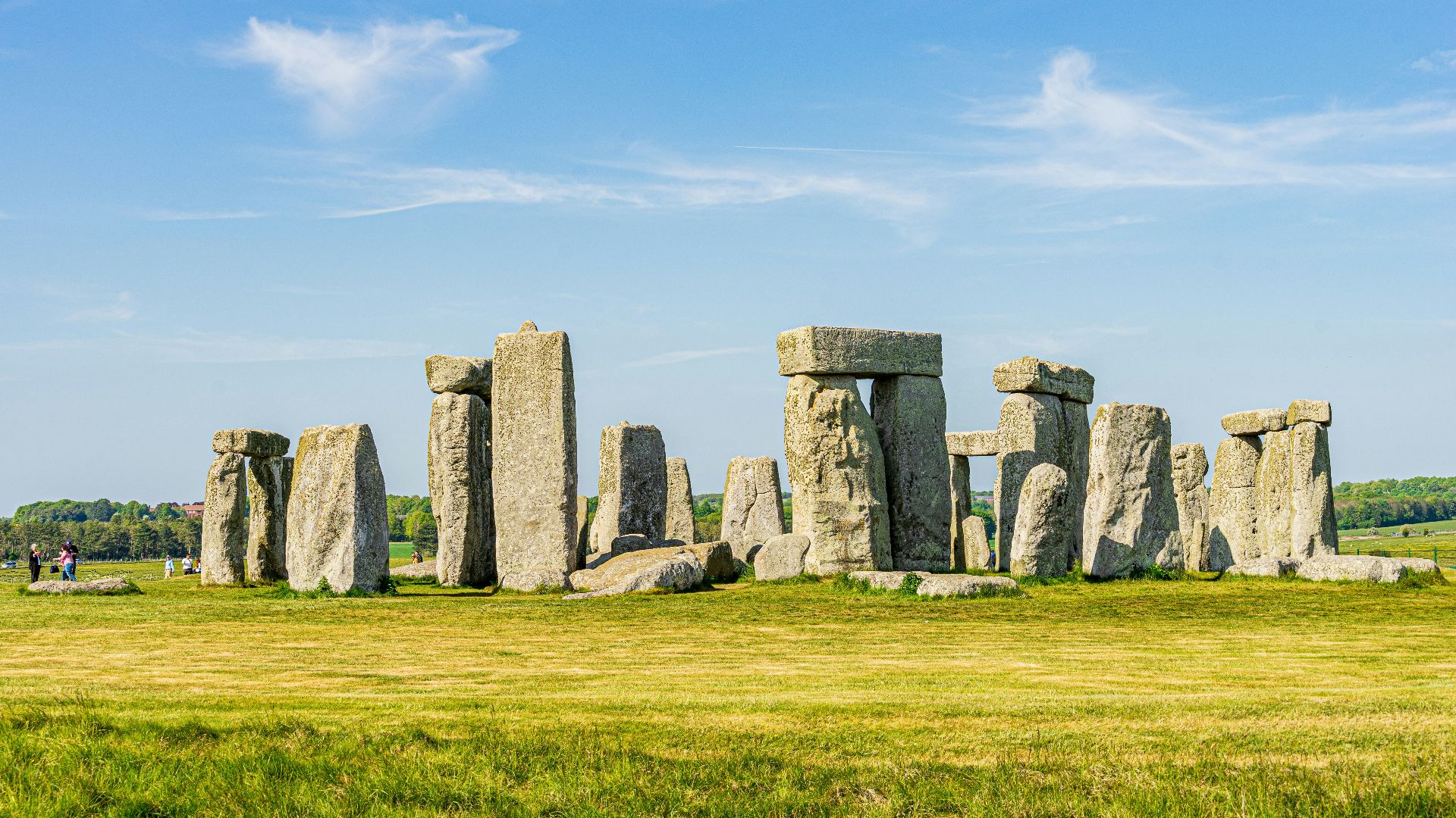 gray rock formation on green grass field under blue sky during daytime