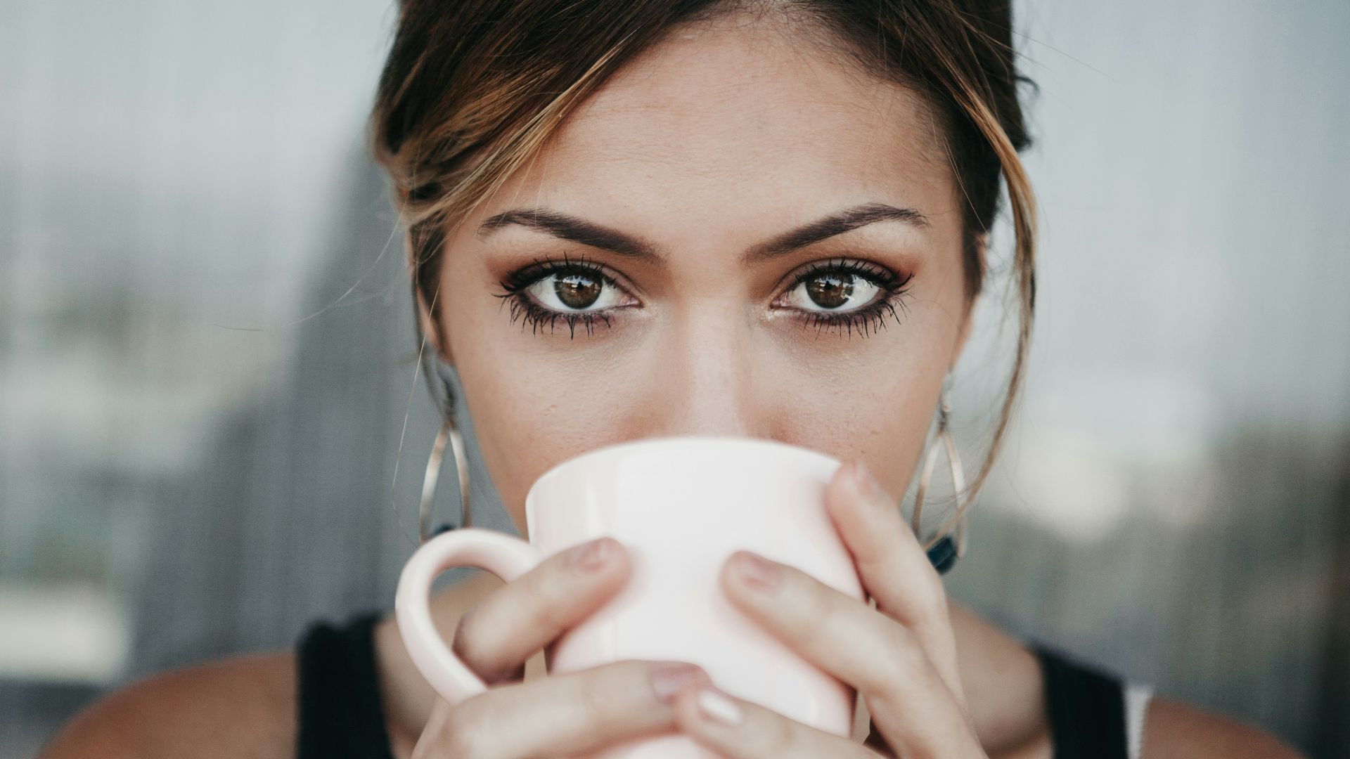 woman drinking from white coffee cup