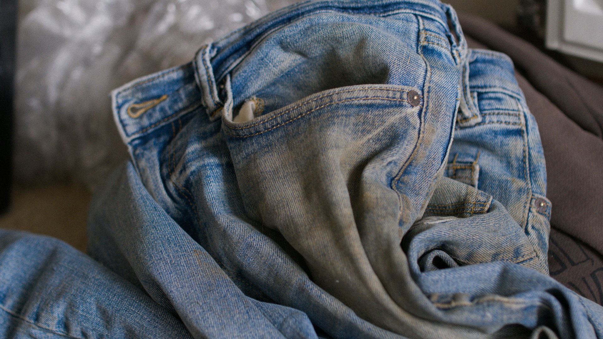 a pile of jeans sitting on top of a bed