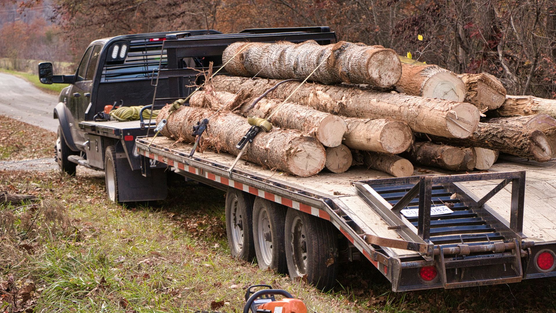 A flatbed truck loaded with logs on a dirt road.