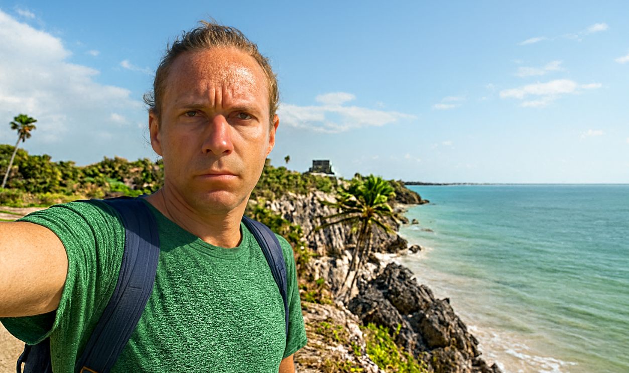 Young man taking selfie portrait in front of ancient Mayan temple in Mexico having fun exploring while on vacations, Tulum