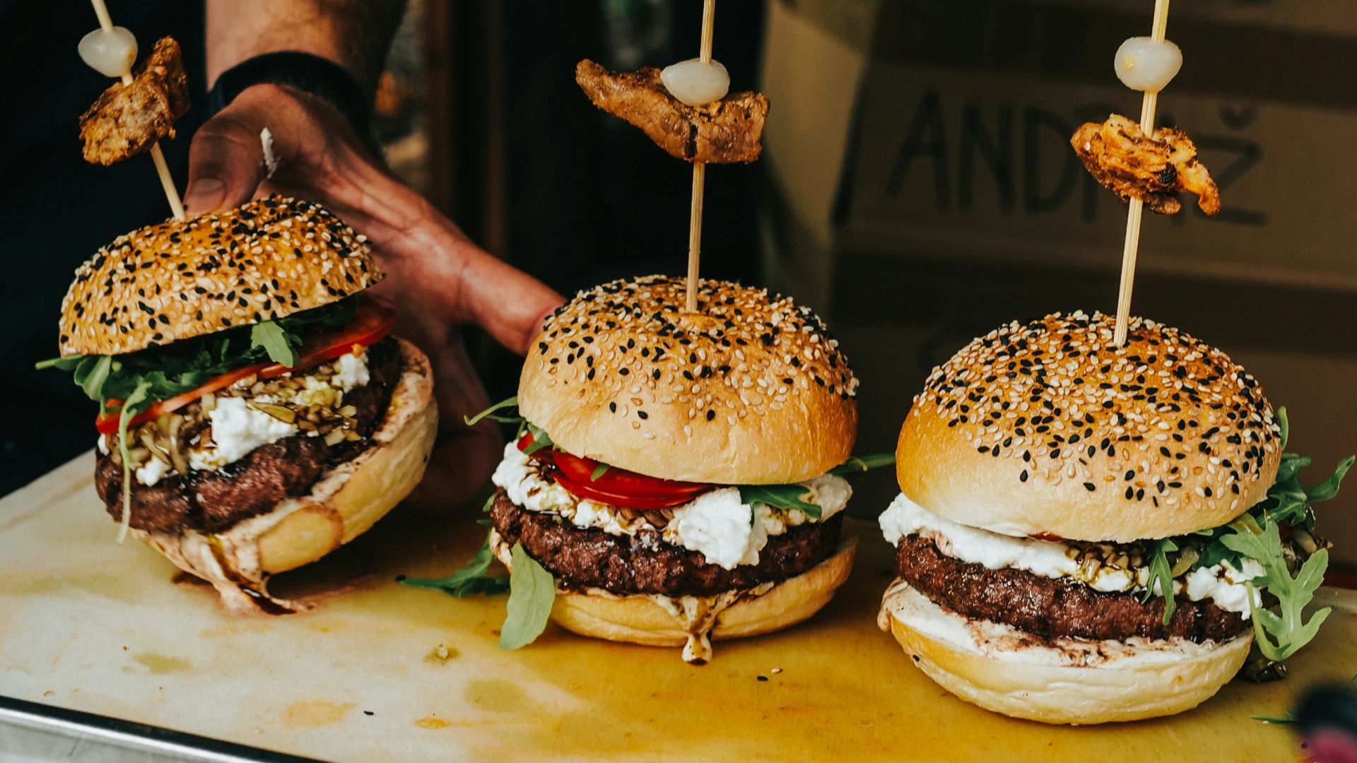 person holding burger with patty and cheese