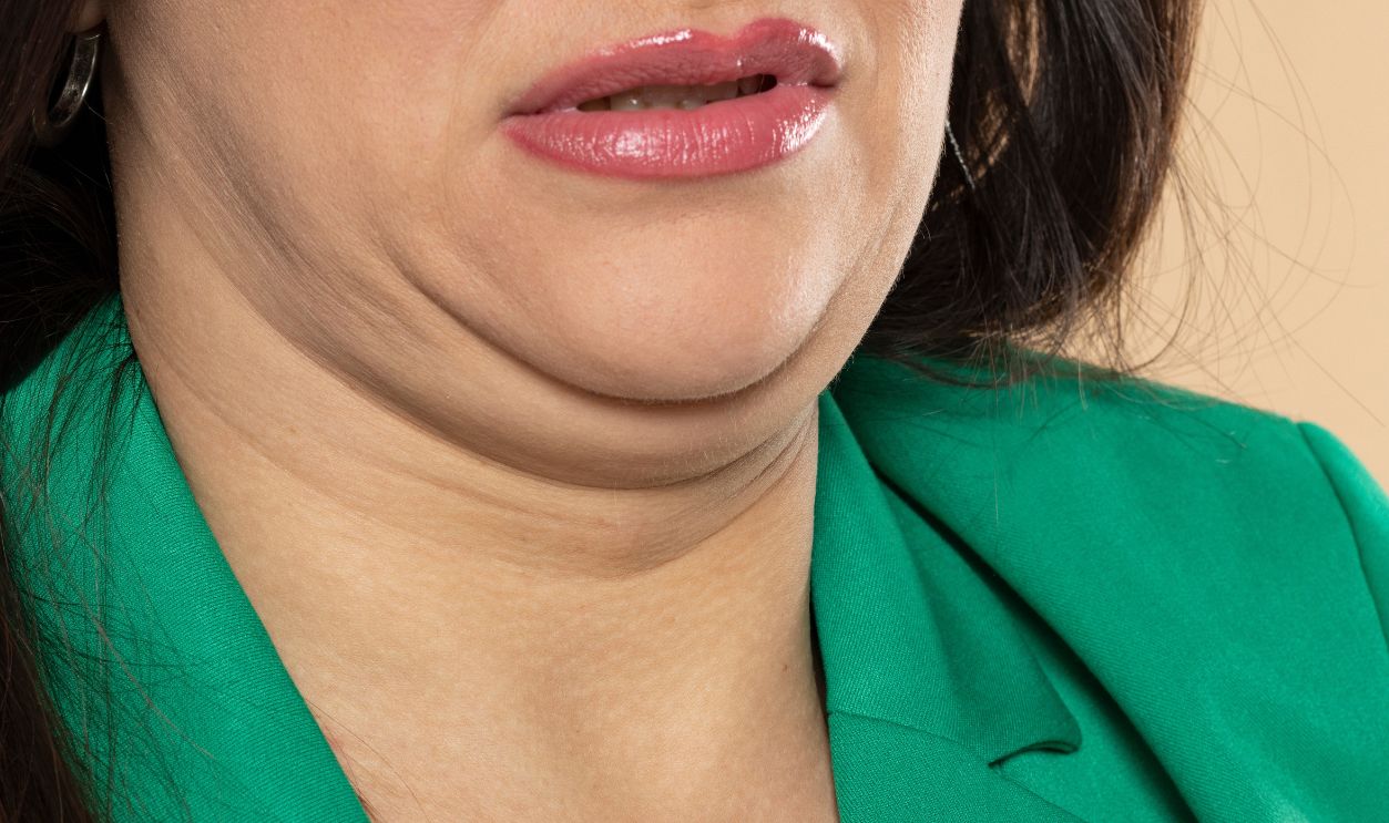 Young woman with double chin on beige studio background, closeup. Front view