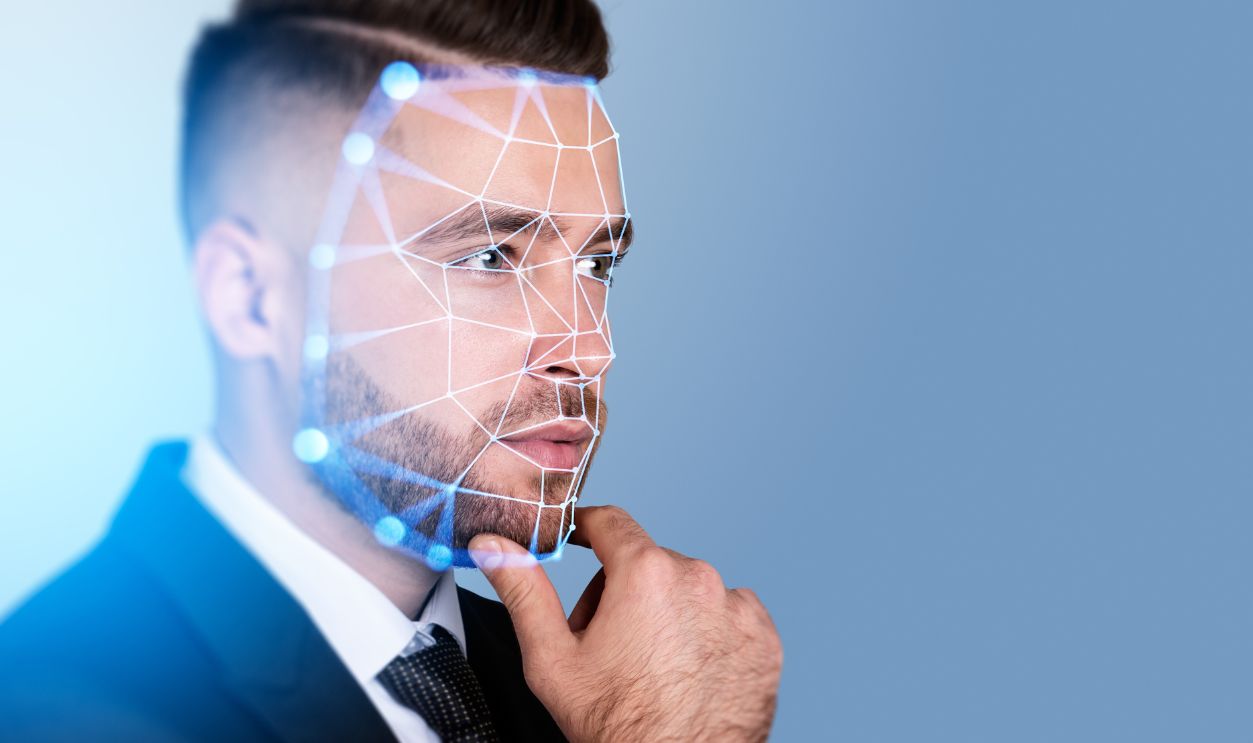 Serious handsome businessman touching chin with facial recognition by digital interface with line connection hologram. Concept of modern technology of artificial intelligence biometric scanning