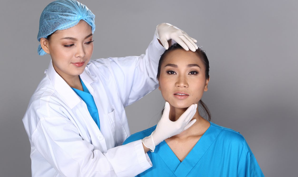 Asian Doctor Nurse check face forehead chin structure before plastic surgery and inject beauty chemical syringe to patient, Studio lighting grey background