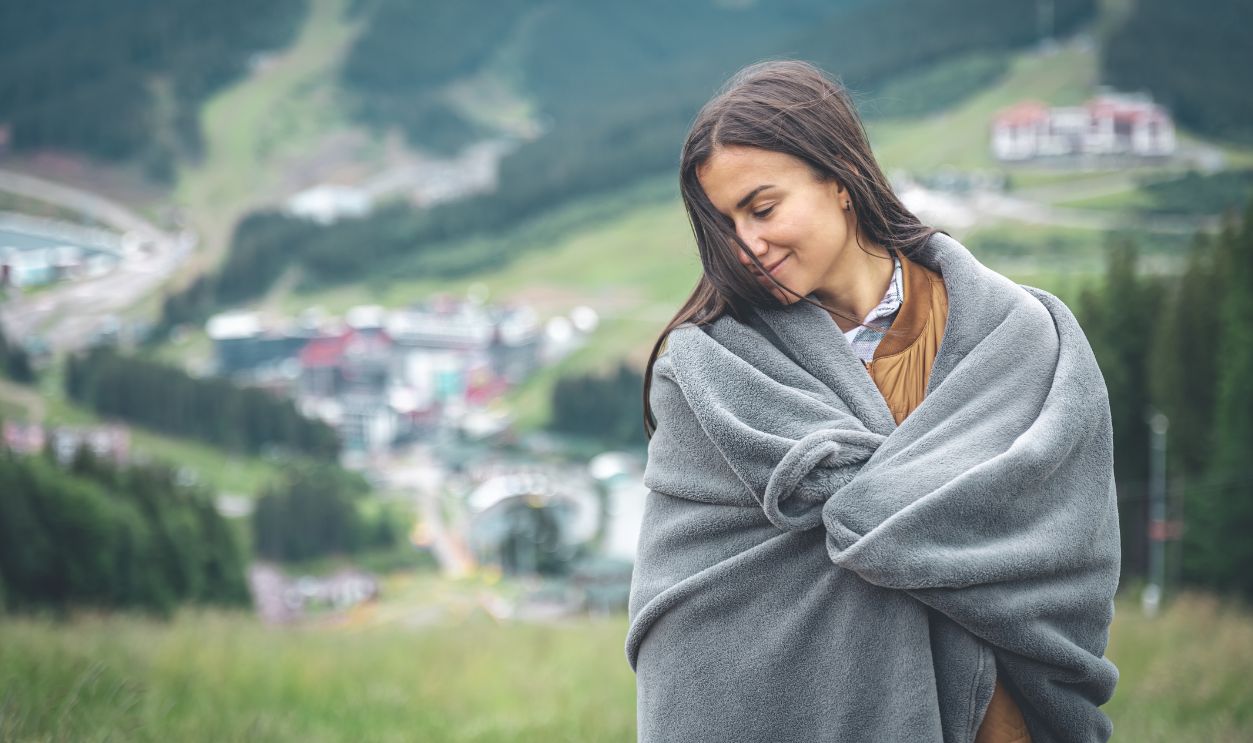 A young woman wrapped in a blanket in the mountains.