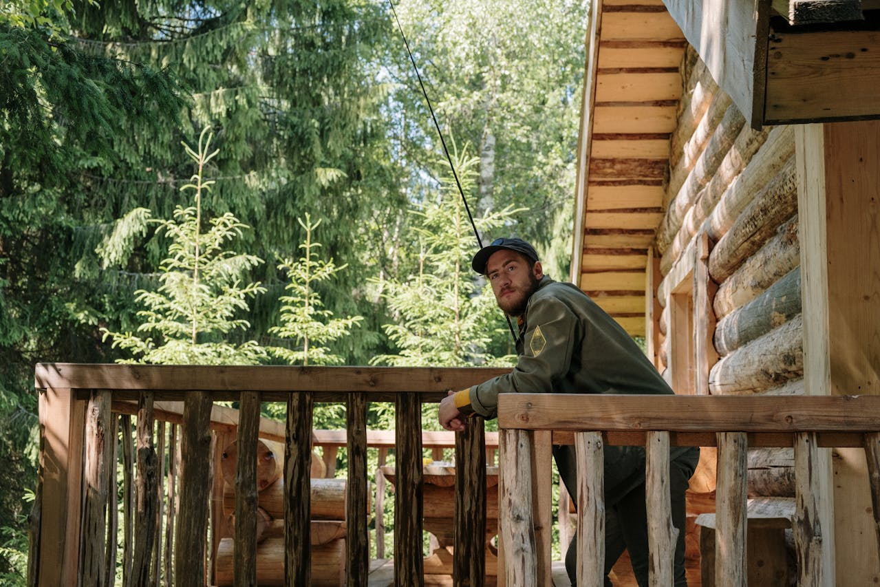 Man in Gray Jacket Sitting on Brown Wooden Porch