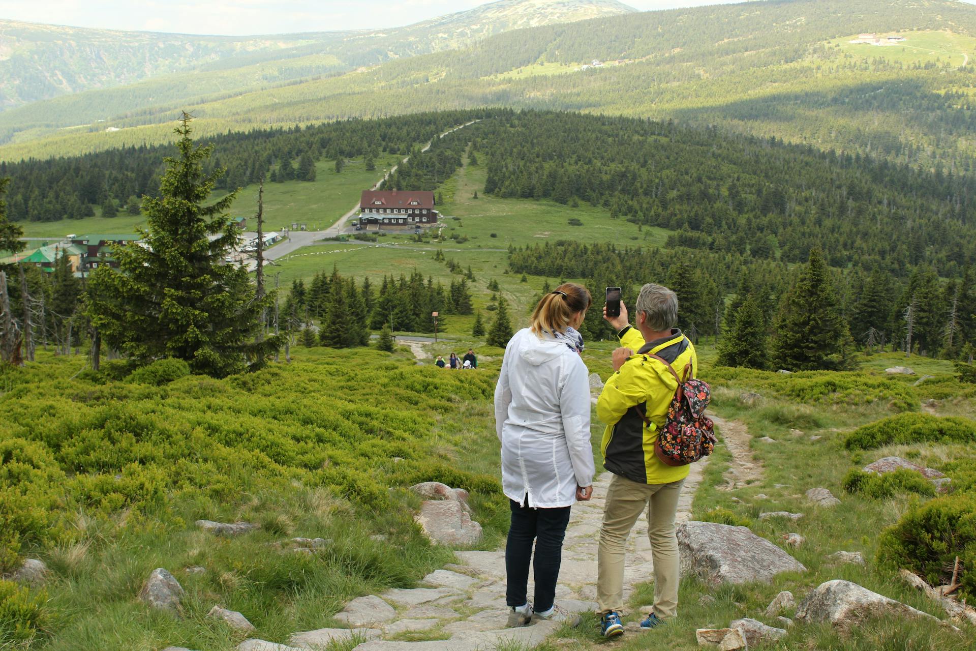 Woman Beside Man on Top of Mountain Taking Selfie
