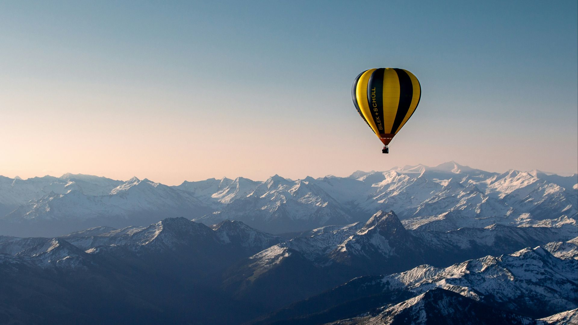 yellow and blue hot air balloon flying over the mountains during daytime