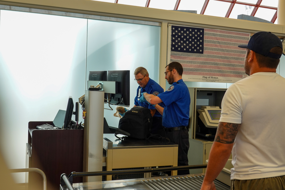 Two TSA Security employees checking a backpack for potentially dangerous items