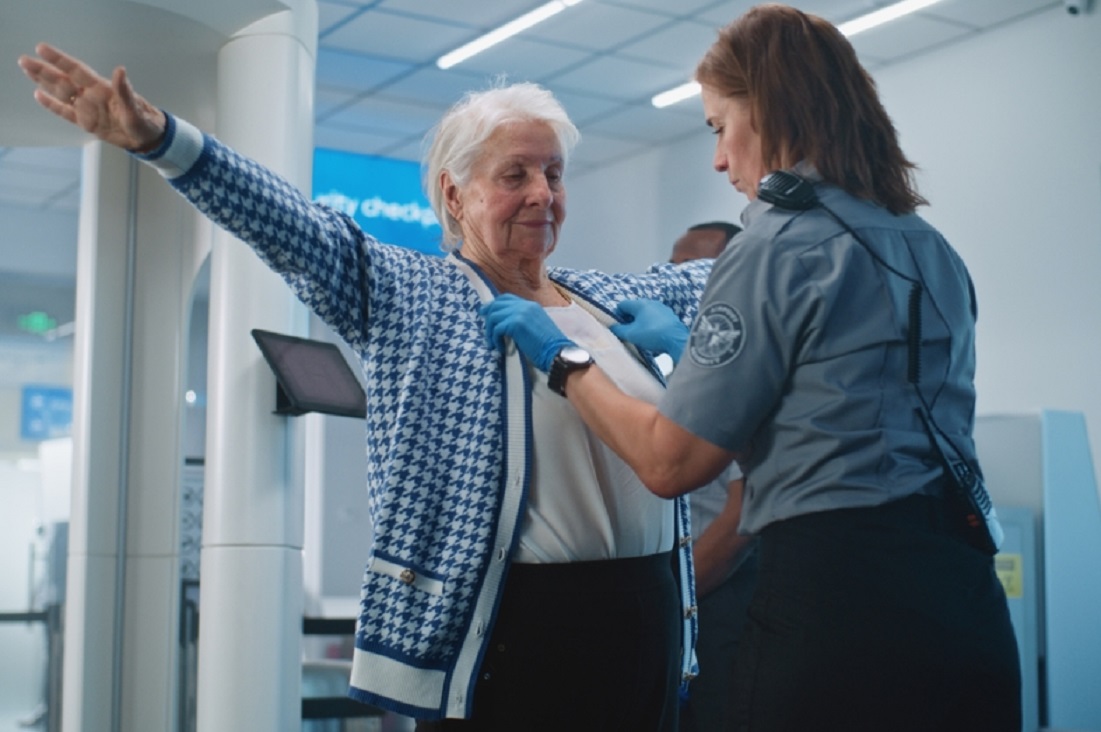 Security Checkpoint in Airport Terminal: Female Security Officer Inspects Elderly Woman