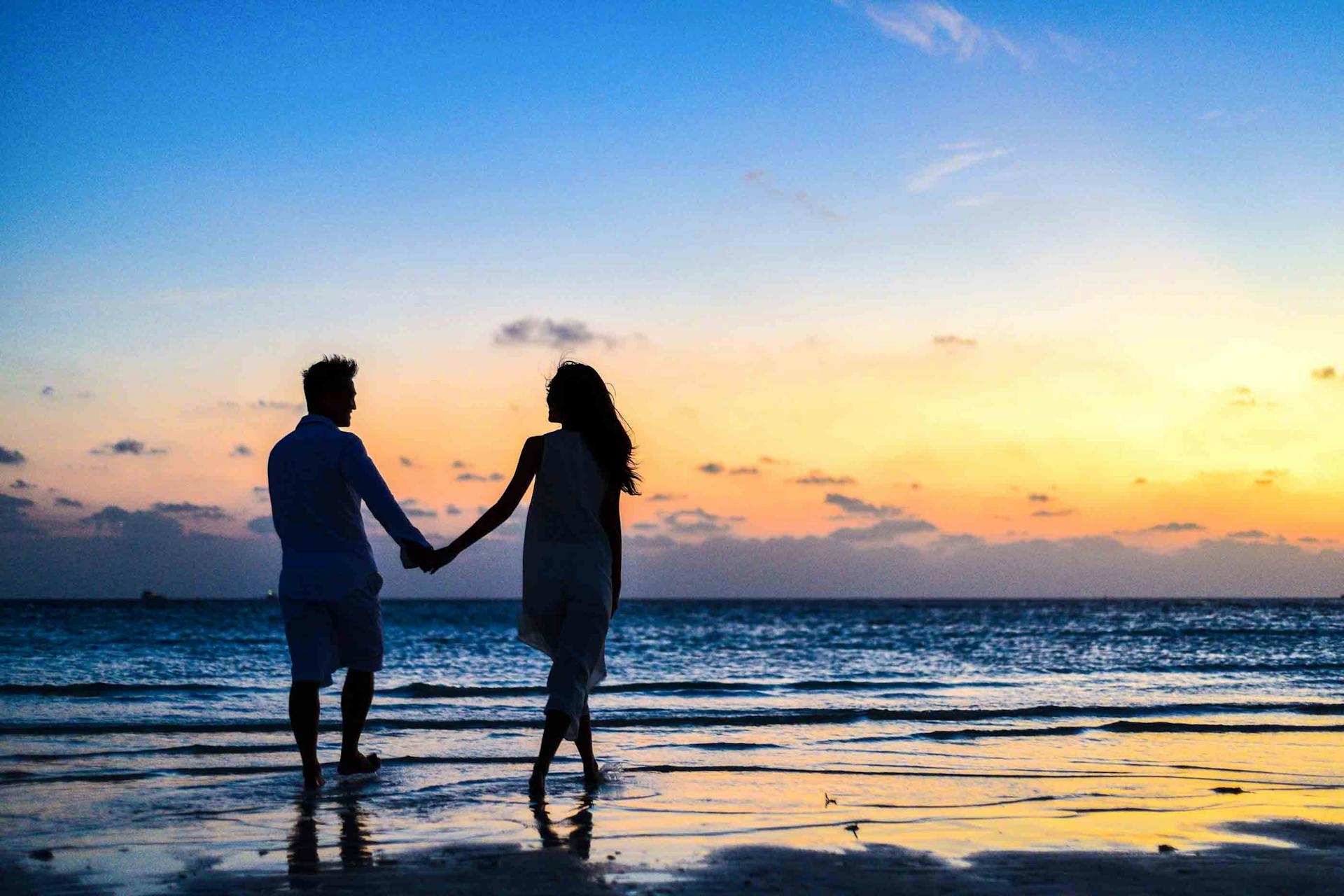 Man and Woman Holding Hands Walking on Seashore