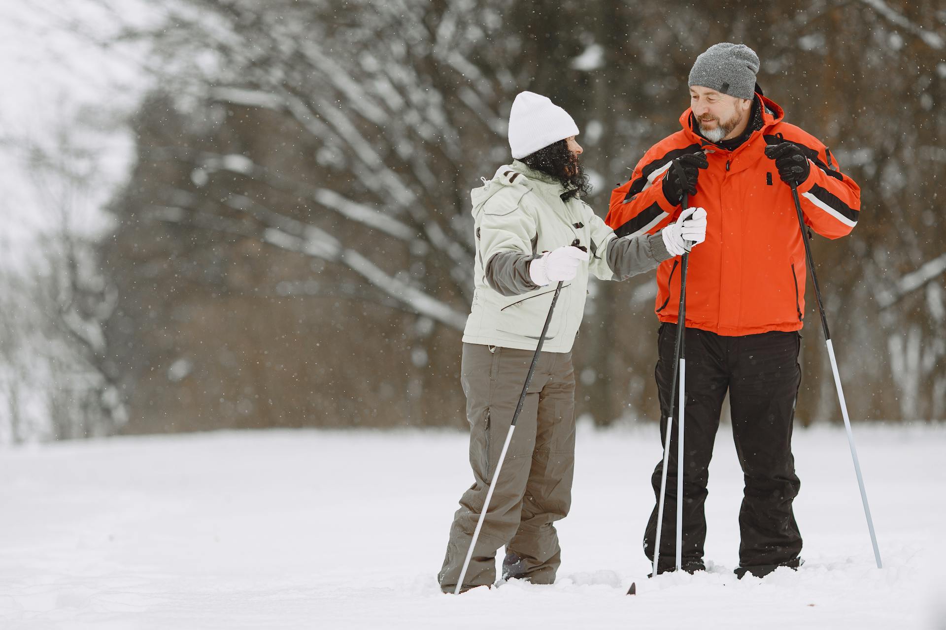Man in Red Jacket Talking to a Woman While Holding Ski Poles