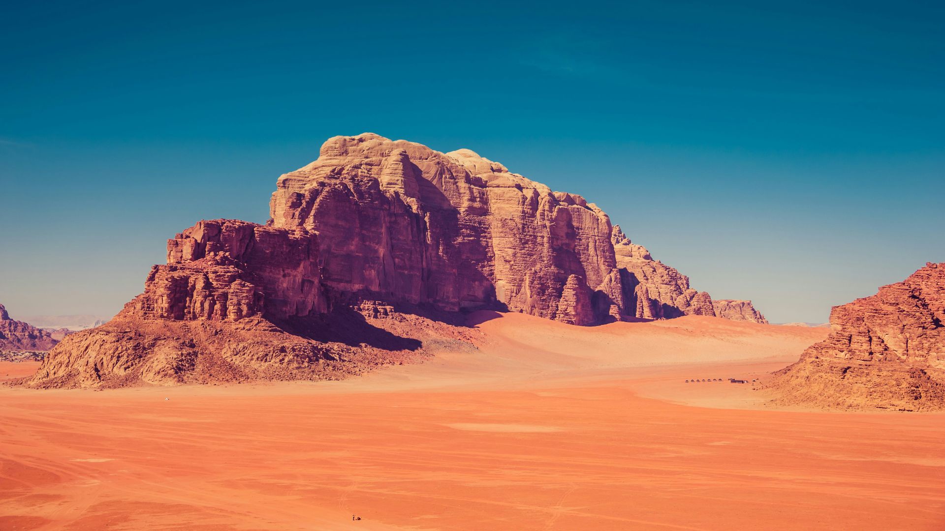 brown rock formation surrounded by sand dunes