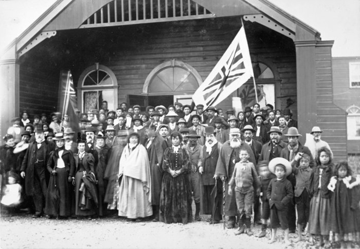 Maori group in the porch at the opening of the large two-storied Parliament house - 1897