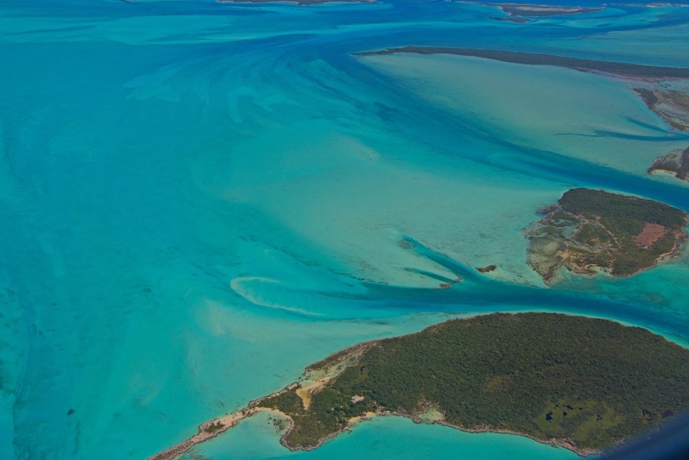 Descending over vibrantly colored blue waters around the Exumas, Bahamas