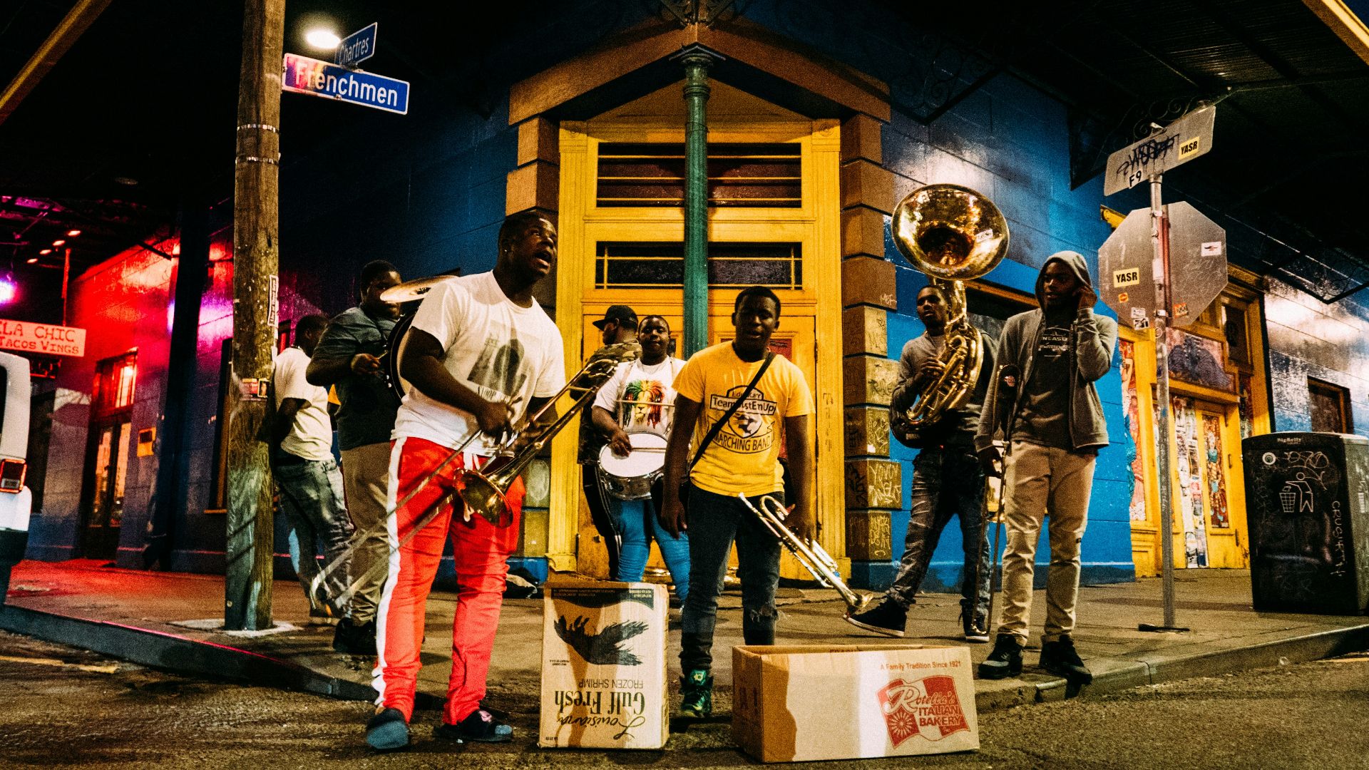 people holding musical instruments while standing on street during nighttime