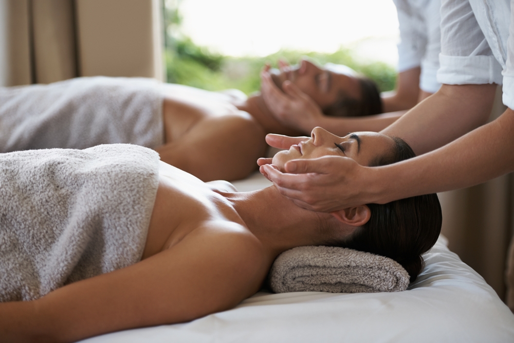 Hands, face massage and couple in spa to relax on bed