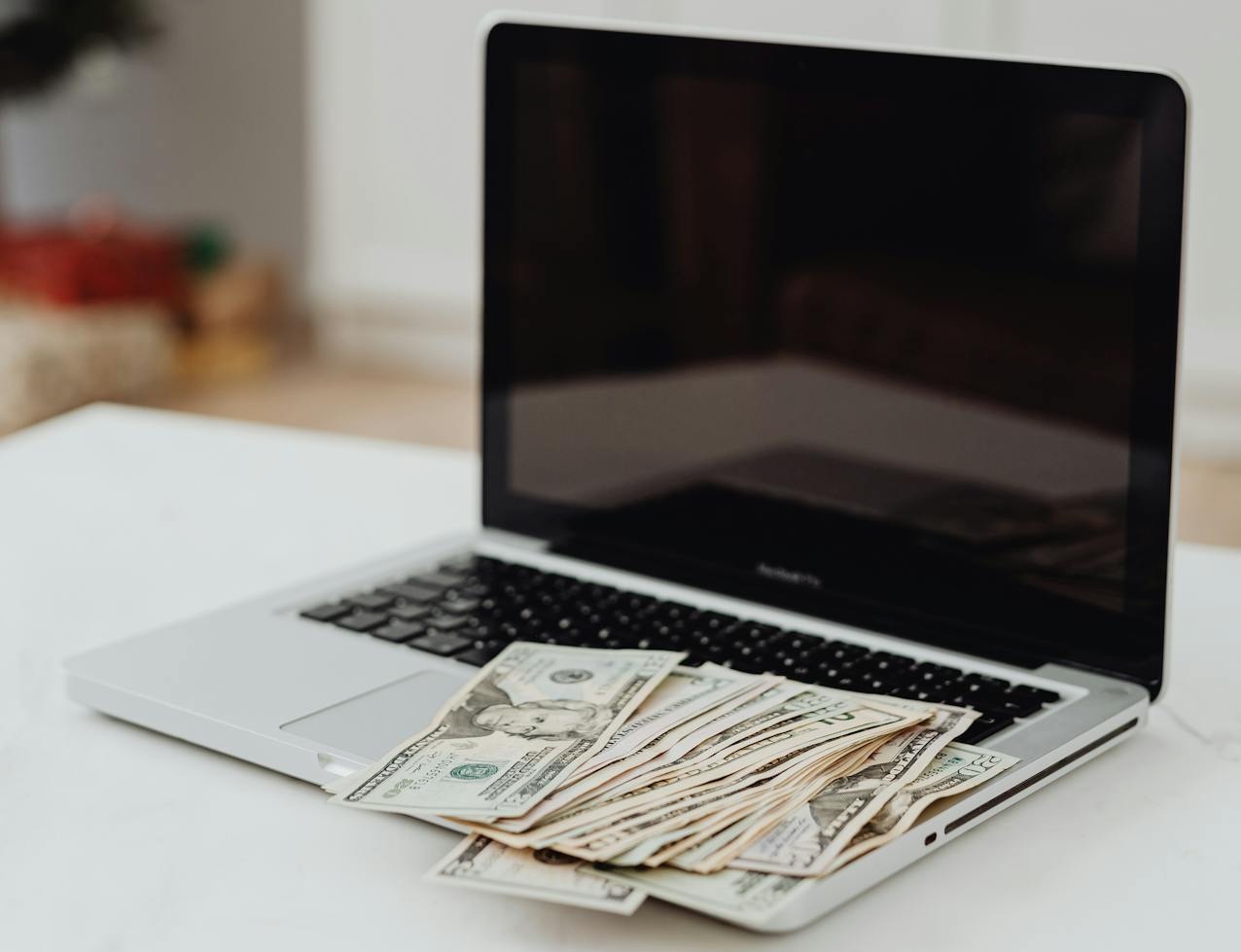 Selective Focus Photo of a Silver Laptop with Banknotes