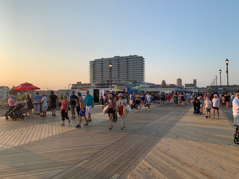 People enjoy strolling along the wooden boardwalk on a summer vacation afternoon in Asbury Park, New Jersey, on the Jersey Shore